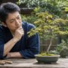 幹が細いもみじ盆栽を見ながら育て方を考える日本人男性
