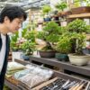 ホームセンターの園芸売場でミニ盆栽と盆栽用品を選ぶ日本人男性